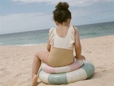 Pige på stranden i tofarvet badedragt i råhvid og brun med flæsedetalje fra Lil Atelier 13239462